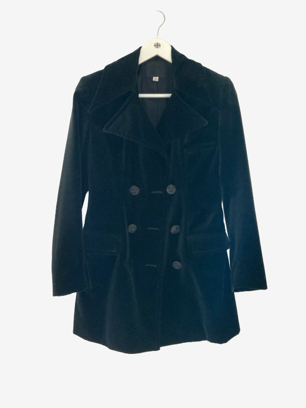 A black double-breasted velvet blazer coat hanging on a white hanger against a plain white background.