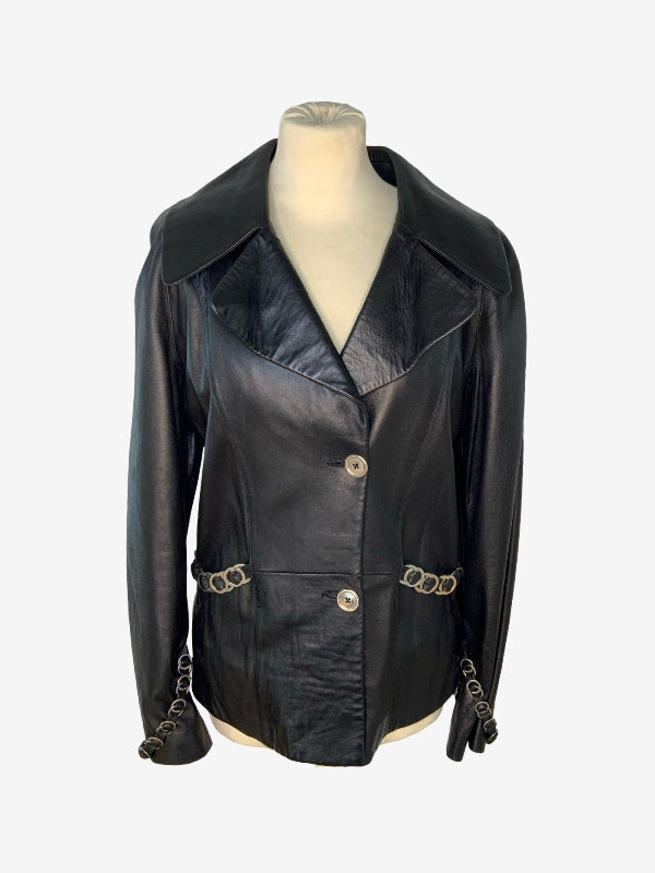 A black leather jacket with wide lapels, front buttons, and chain-link details on the waist and cuffs, displayed on a mannequin torso against a light gray background.