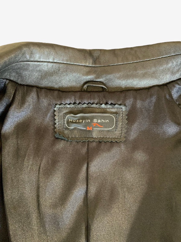Close-up of the interior waistband of a black leather jacket, showing a stitched label that reads 'Huseyin Sahin'.