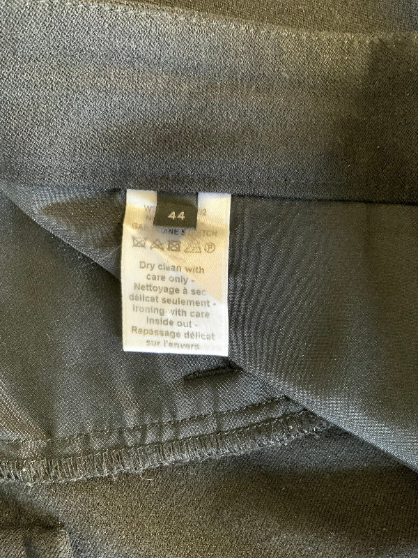 Close-up of a garment's interior label on black fabric, showing care instructions and a size marker.