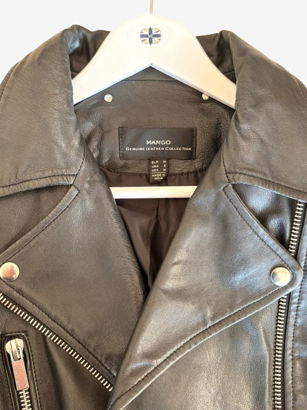 A close-up of a black leather motorcycle jacket on a white hanger, showing the brand label 'MANGO' and silver-tone hardware.