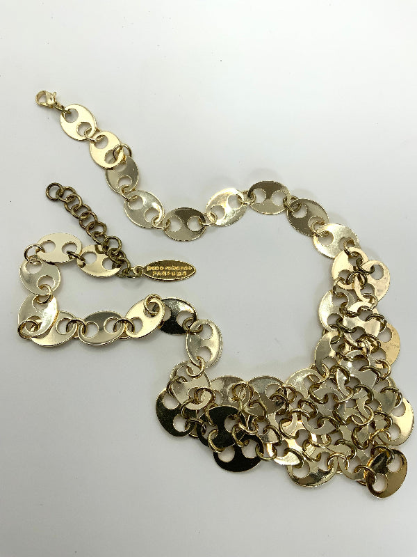 A gold-tone chain necklace with large, irregular disc-like links and a small hanging tag, photographed on a plain white background.