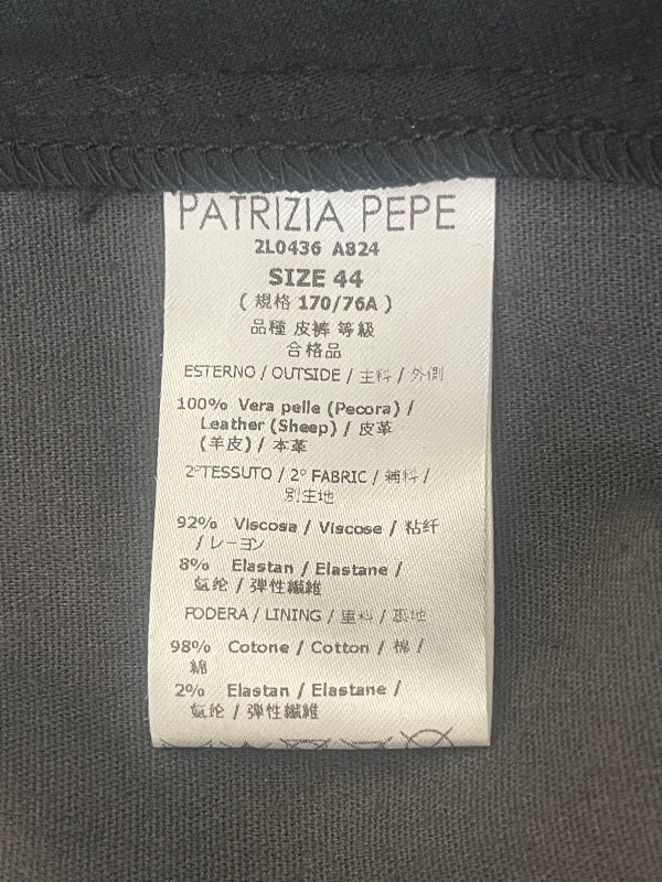 A close-up of a garment's interior label reading PATRIZIA PEPE, size 44, with fabric composition details in multiple languages on a black fabric background.