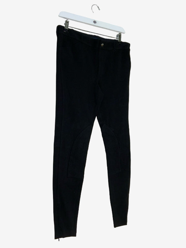 Black skinny pants hanging from a white plastic hanger against a light gray background.