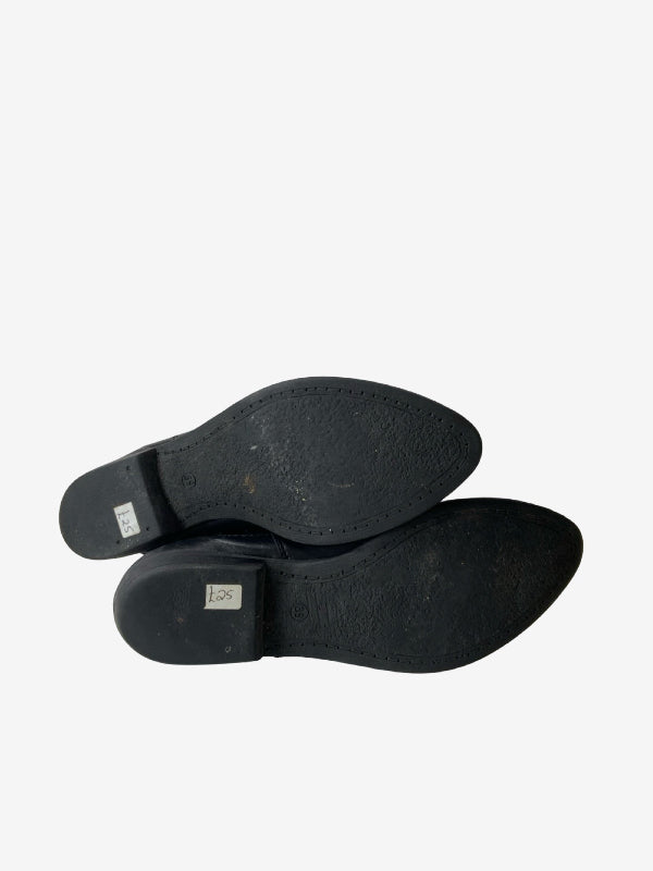 A pair of black leather dress shoes shown from the sole view, displaying the textured black rubber outsoles against a plain white background.