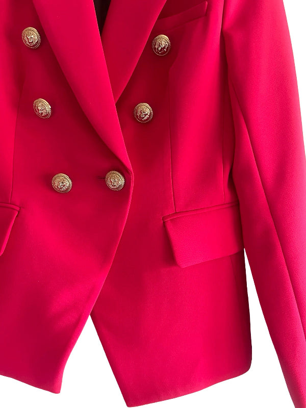 A close-up of a bright raspberry red pink double-breasted blazer with ornate gold buttons, set against a plain white background.