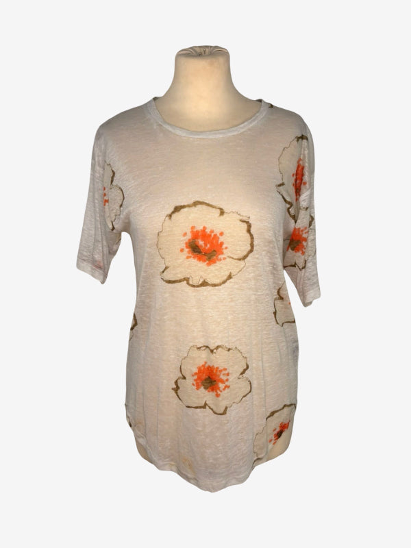 A short-sleeve tunic top displayed on a mannequin torso against a plain white background. The top is a light beige or cream color with a pattern of large flowers outlined in brown and filled with orange and red centers.