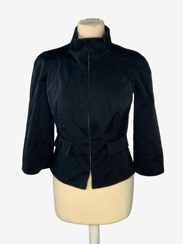 A black cropped jacket with a high stand collar and three-quarter sleeves, displayed on a cream-colored dress form mannequin against a light gray background.