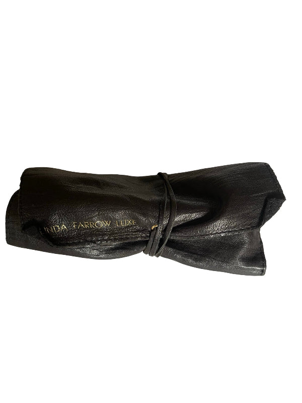A rolled-up black leather pouch or clutch tied with a matching black cord, featuring gold foil branding that reads 'NIDA FARROW LUX' on a plain white background.