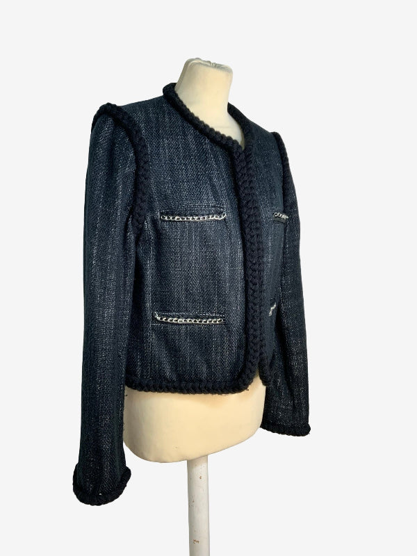 A charcoal tweed jacket with black trim and silver chain details, displayed on a cream-colored mannequin torso against a light gray background