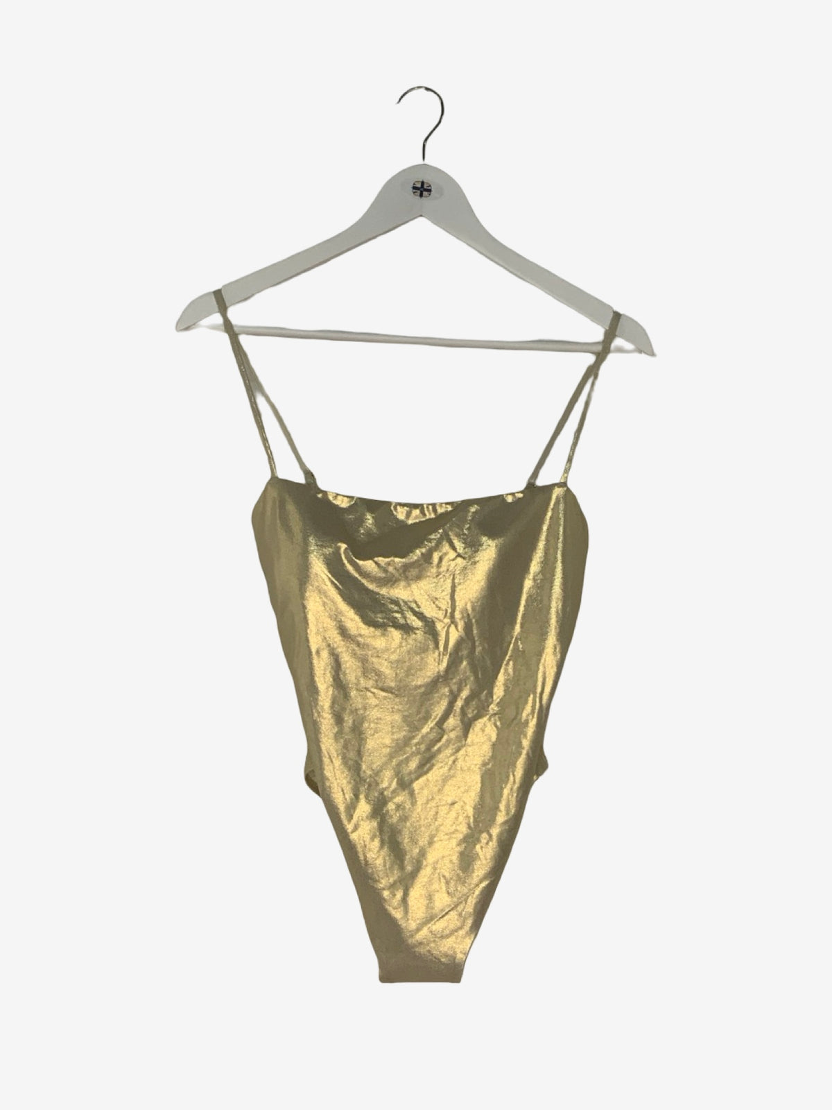 A metallic gold bathing suit with thin spaghetti straps, hanging on a white wooden hanger against a plain white background.