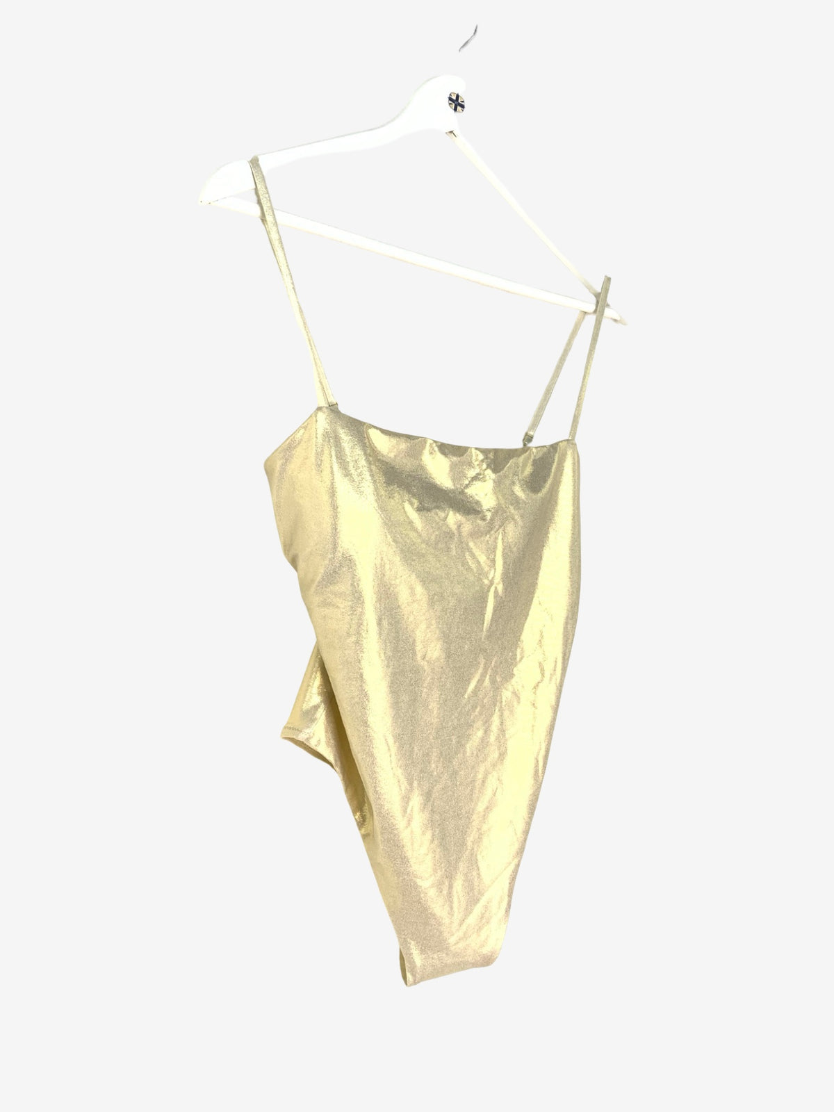 A metallic gold swimming costume with thin spaghetti straps, hanging on a white plastic hanger against a solid light gray background.