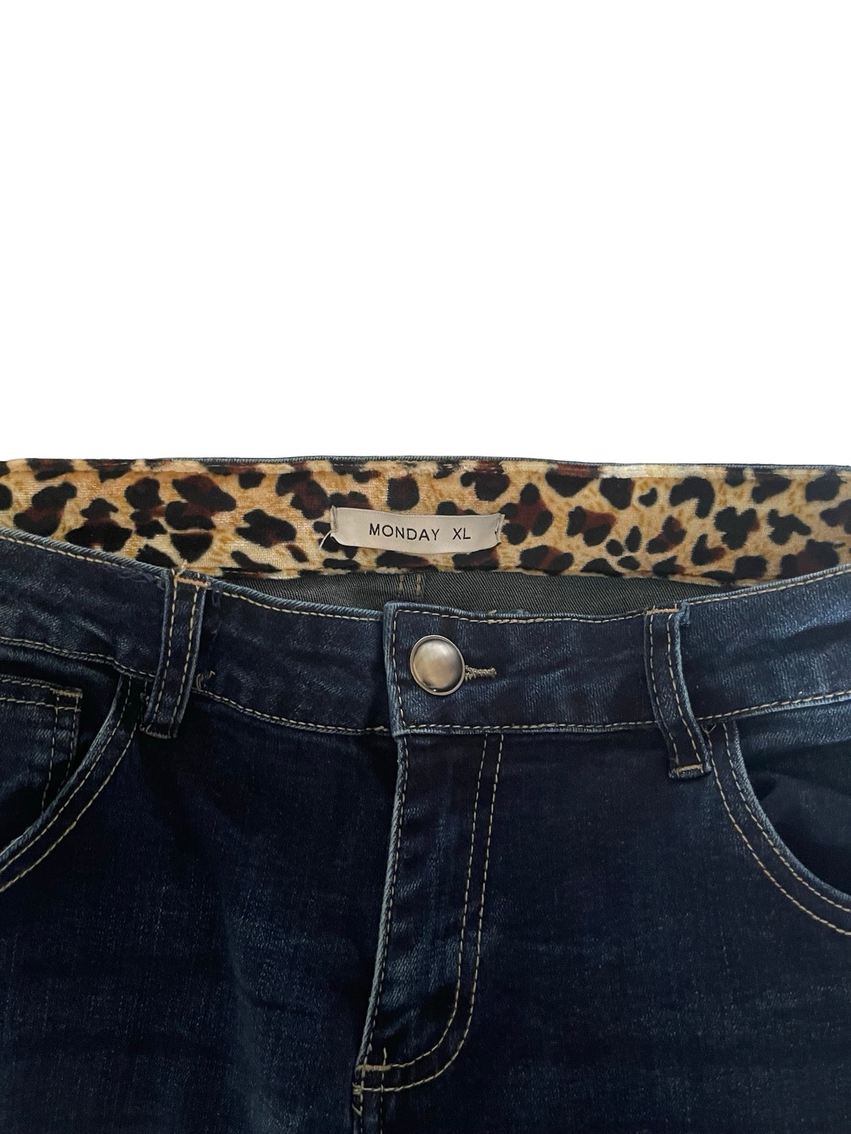 Close-up of the waistband of dark blue denim jeans with a leopard print inner lining and a visible 'MONDAY XL' size label.