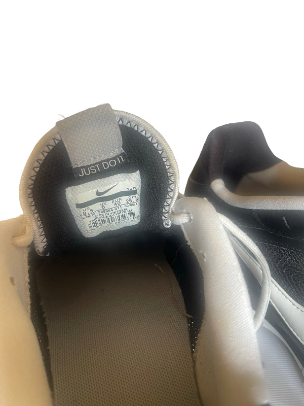 Close-up of the inside collar of a Nike sneaker showing the 'JUST DO IT' tag with a Nike swoosh, alongside the white and black exterior of the shoe.