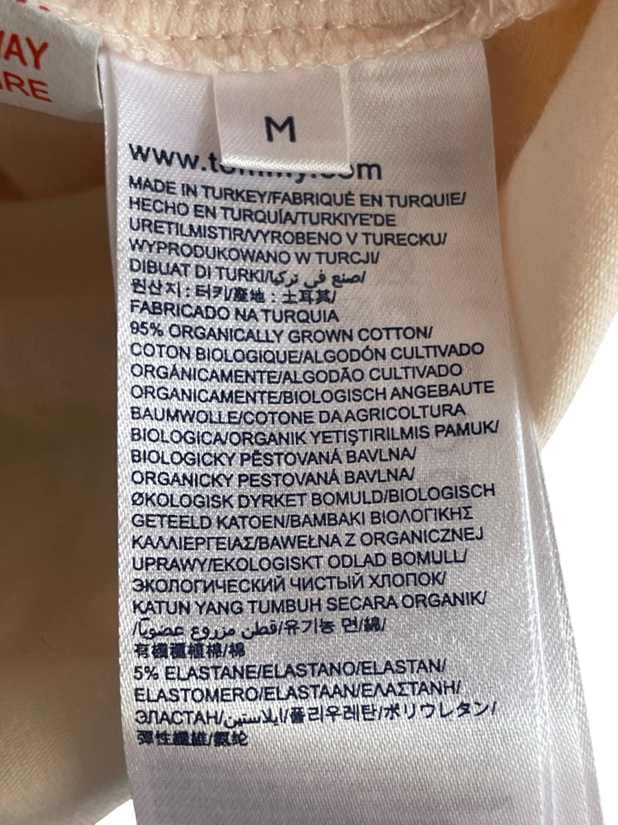 Close-up of a white garment tag with black text showing product details, including 'www.tommy.com’