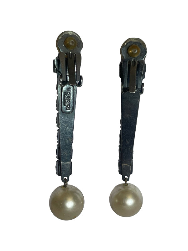 A pair of vintage clip-on earrings featuring dark metal clips with a dangling round pearl at the bottom, shown against a plain white background.