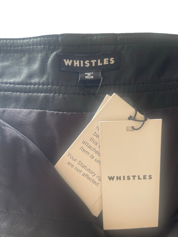 Close-up of the waistband of black Whistles trousers, showing the black leather-like texture, the black brand label, and two attached white paper tags.