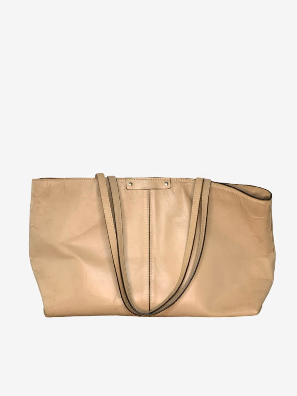 A large beige leather tote bag with double shoulder straps and a central vertical seam, shown against a plain light gray background.