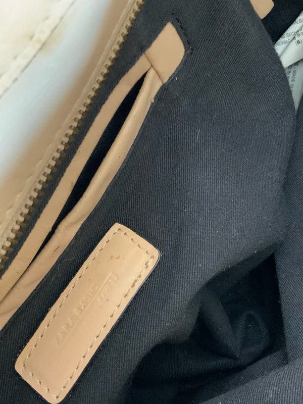 Close-up of a black canvas bag interior with beige leather trim, zipper, and a stitched brand patch reading Zara Basic.