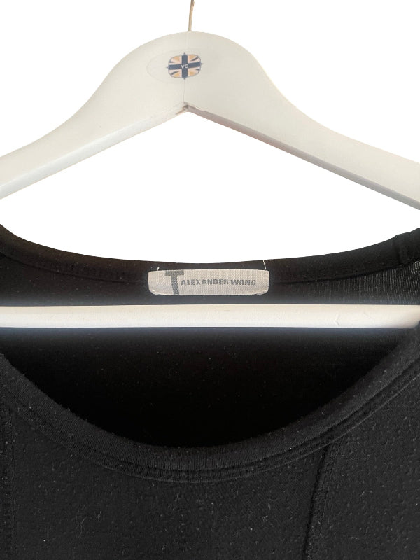 Close-up of a black top hanging on a white hanger against a white background, with a visible neck label reading Alexander Wang.