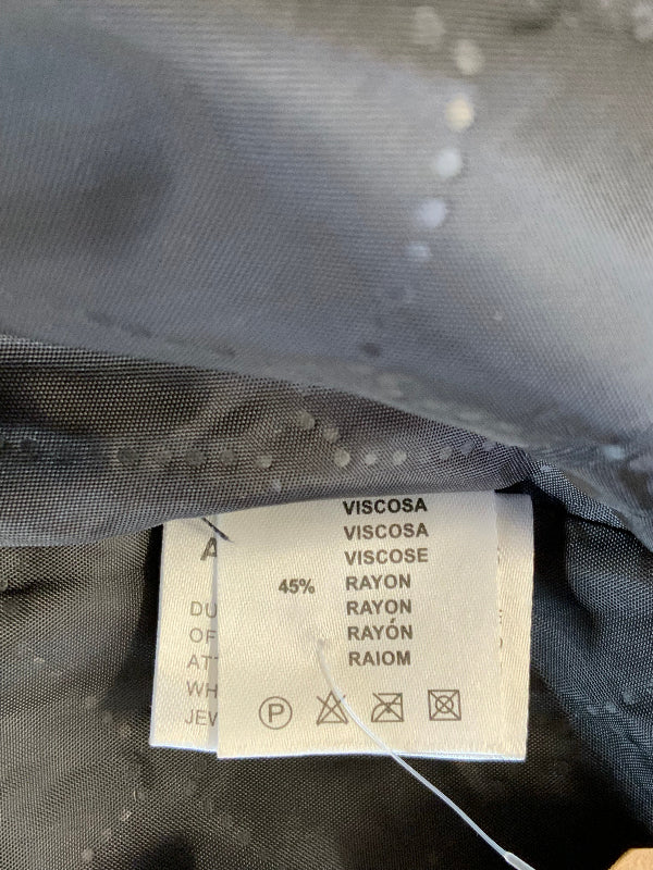 Close-up of a garment's interior label showing fabric composition and care symbols on a dark gray textured material.