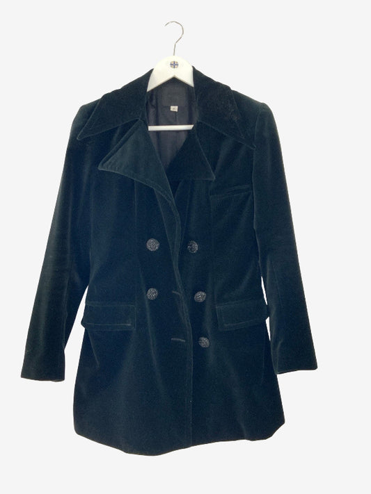 A black velvet double-breasted coat with a wide collar and dark buttons, hanging on a white hanger against a light gray background.