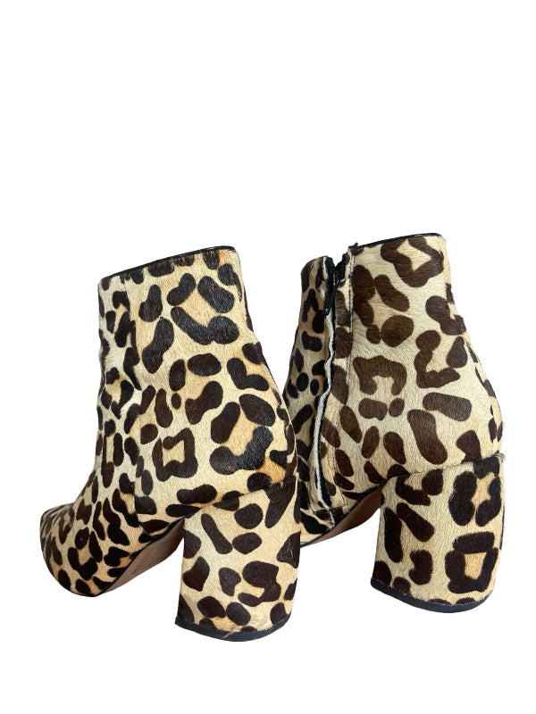 A pair of ankle boots with a leopard print pattern in beige, brown, and black, featuring a block heel and side zipper.