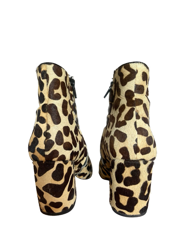 A pair of ankle boots with a leopard print pattern in beige, brown, and black, shown from the back on a white background.