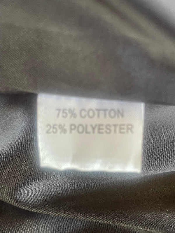 Close-up of a fabric label reading '75% COTTON 25% POLYESTER' sewn onto black satin lining fabric.