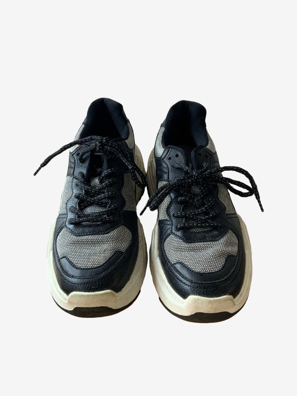 A pair of low-top sneakers in black and gray mesh with thick off-white chunky soles, shown from a front-facing perspective on a light gray background.