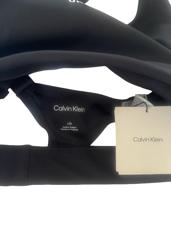 Close-up of a black Calvin Klein garment showing the inner neck label and a white Calvin Klein hangtag against a white background.