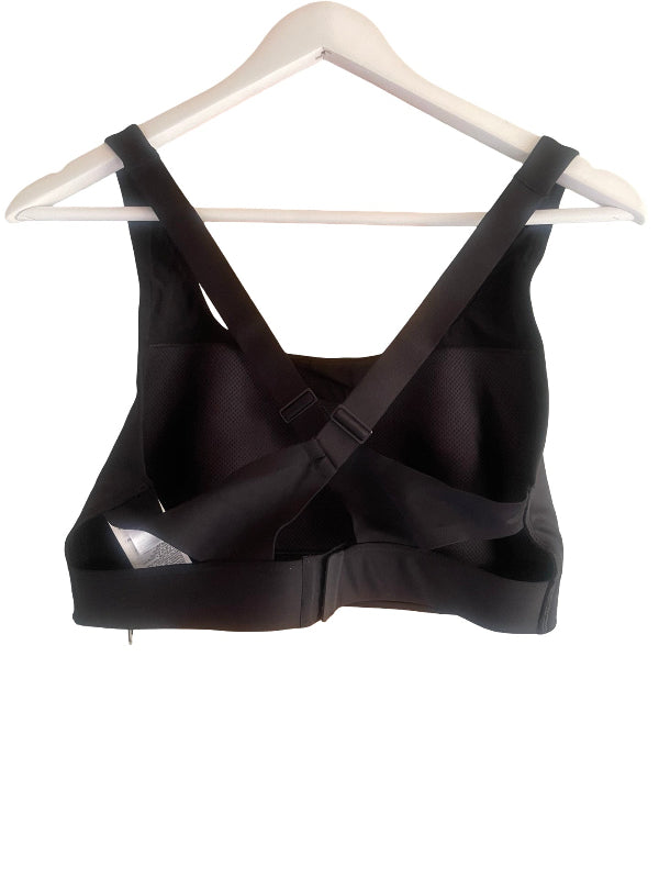 Black strappy support bra hanging on a white plastic hanger against a white background.