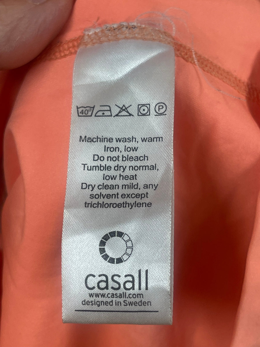 Close-up of a garment's interior care label reading 'casall' on peach-colored fabric.
