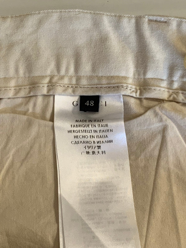 Close-up of the inside waistband of a beige garment, showing a white size tag with text including 'G 48 I' and 'MADE IN ITALY'.