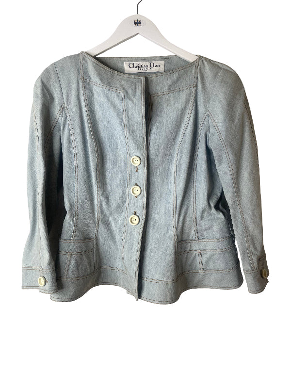 A light blue denim jacket from Christian Dior, hanging on a white hanger against a plain white background.