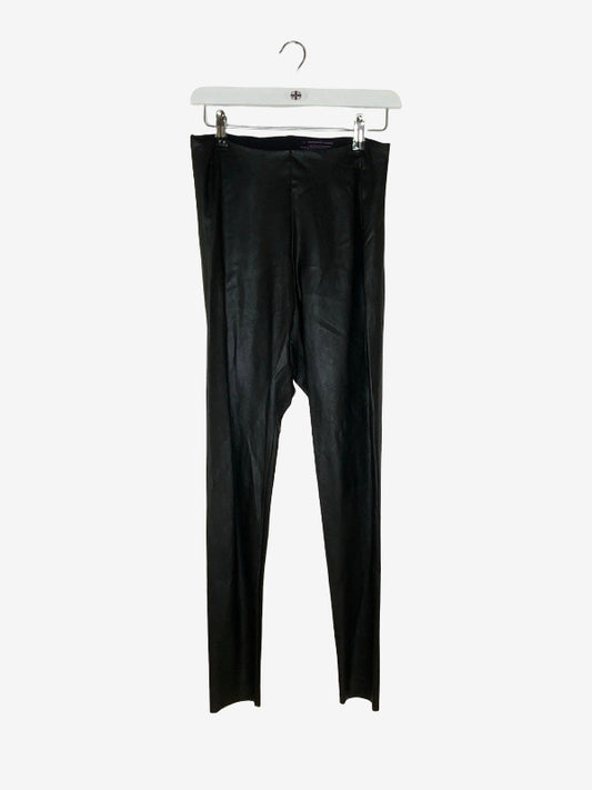 Black faux-leather leggings hanging from a white plastic hanger against a light gray background.