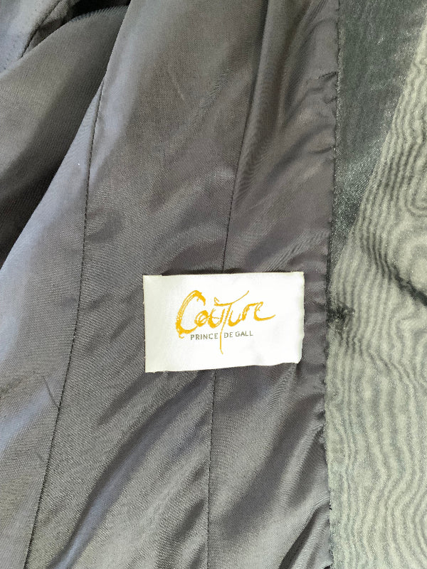 Close-up of a gray  jacket interior with a white sewn-in label reading 'Couture PRINCE DE GALL' in gold script.