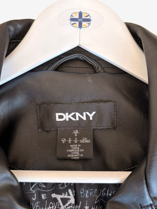 Close-up of a black leather jacket hanging on a white hanger with a DKNY brand label visible inside the collar.