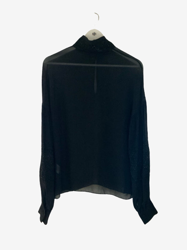 A black long-sleeve blouse with a sheer mock neck and subtle lace detailing on the sleeves, hanging on a white hanger against a light gray background.