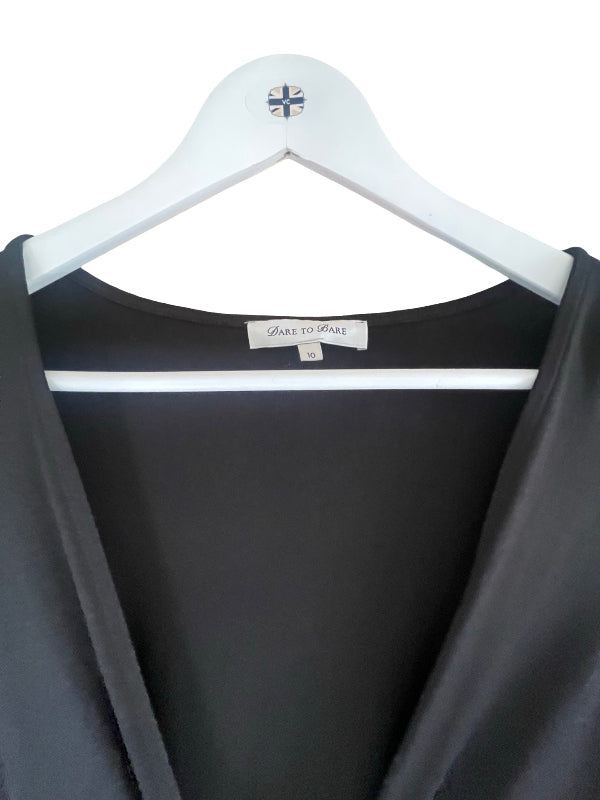 A close-up of a black satin or silk-like garment draped over a white hanger, showing the inner neckline and a visible 'DARE TO BARE' brand label.