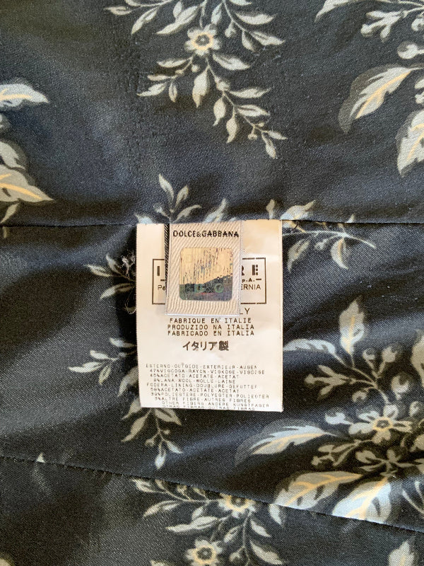 Close-up of a Dolce & Gabbana floral fabric with a white product tag showing the brand name and Italian text.