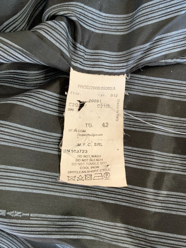 Close-up of a striped garment interior with a sewn-on product label. The fabric is dark gray with thin light gray to white horizontal stripes, and the label reads M.