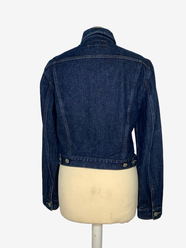 A dark blue denim jacket shown from the back, displayed on a cream-colored dress form mannequin against a plain white background.
