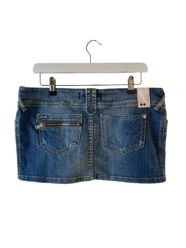 A blue denim mini skirt with zippered back pockets, hanging from a white hanger against a plain white background.