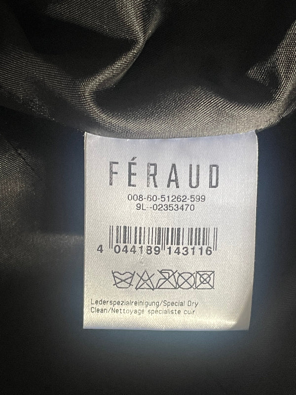 A close-up of a white fabric clothing tag with the brand name FÉRAUD printed vertically, attached to a black  garment.