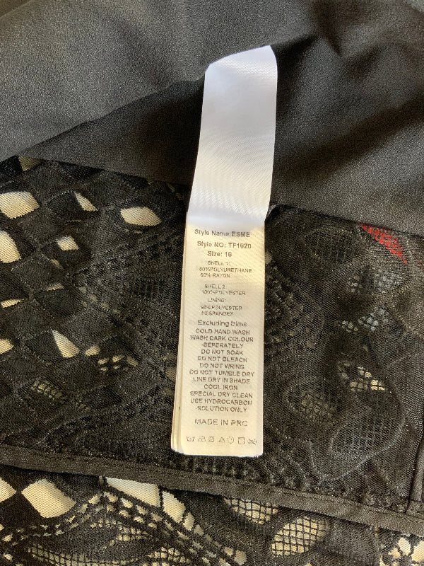 A close-up of a garment tag attached to black lace fabric, showing the brand name 'SILK' and product details.