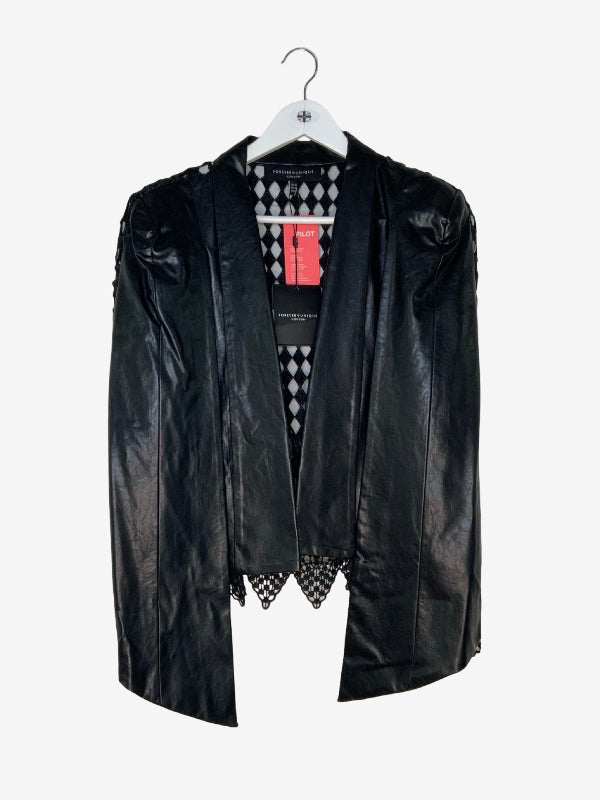 A black faux leather cape with a high collar and structured shoulders, hanging on a white hanger against a light gray background, a black and white diamond-patterned lace back  is visible.