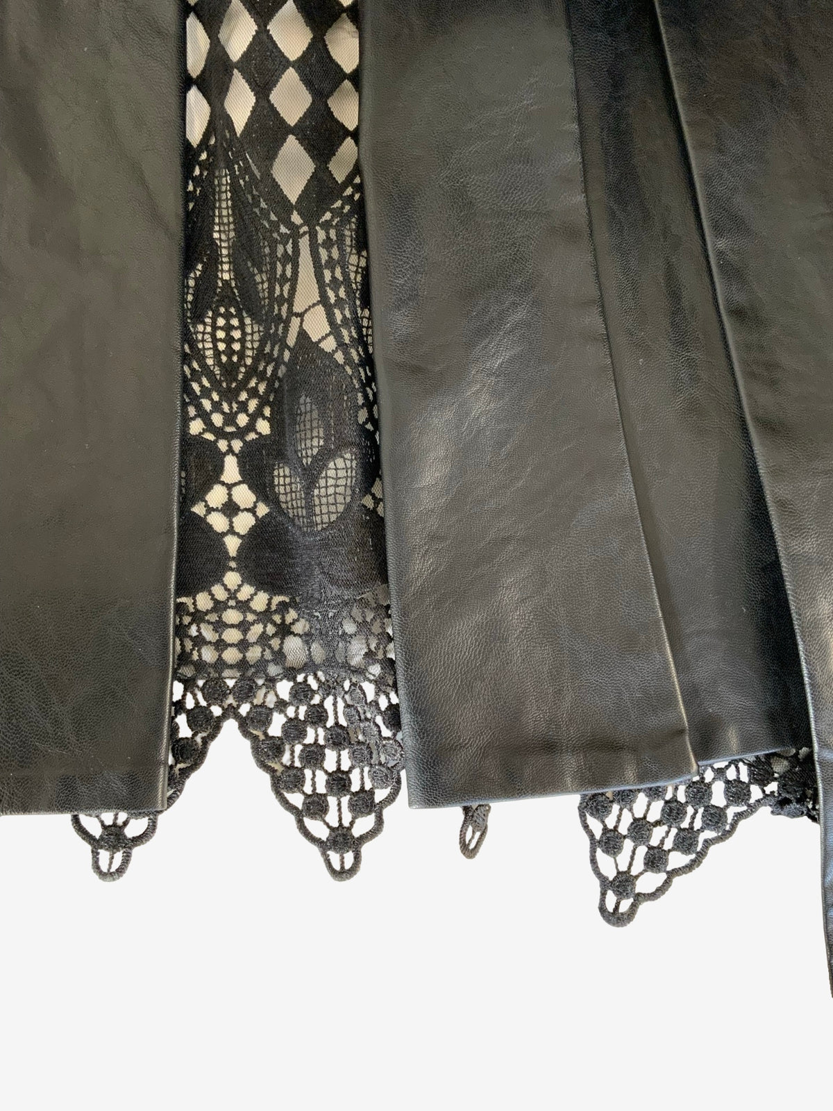 Close-up of a black faux leather garment, likely a jacket or cape, with a black lace insert back, shown against a plain white background.