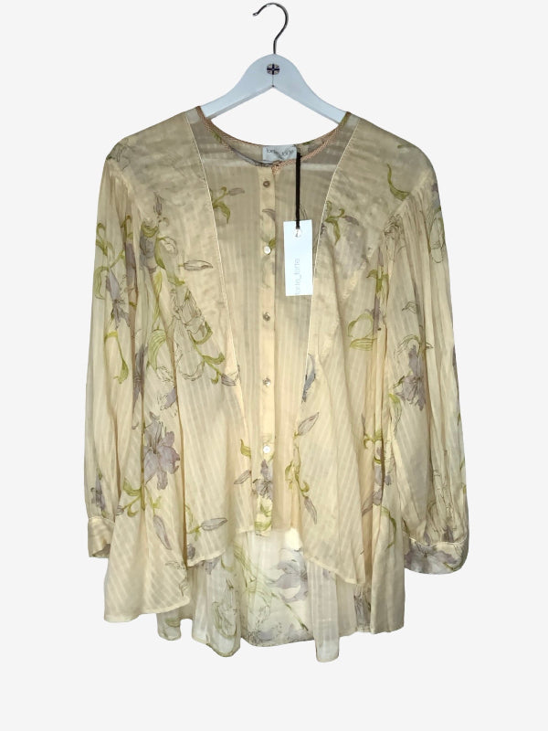 A lightweight butter  apricot blouse with a subtle vertical stripe texture and a muted green and purple floral print, hanging on a white hanger against a light gray background
