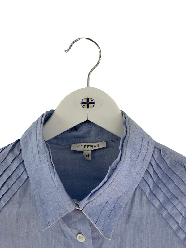 A light blue pleated button-down shirt by GF FERRI hanging on a white hanger with a small flag emblem, shown against a plain white background.